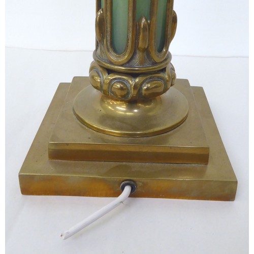 44 - An early 20thC brass table lamp incorporating an opaque, pale green glass column, on a stepped, squa... 