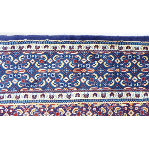 121 - A Persian design carpet, decorated and bordered with repeating geometric patterns, on a blue ground&... 