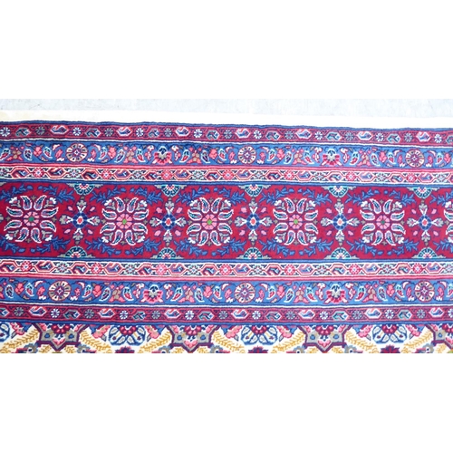 126 - A Persian design carpet, decorated with repeating floral patterns, on a red ground  126