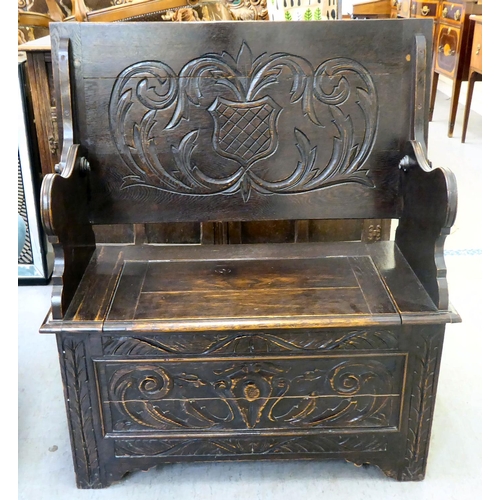 24 - A 1930s stained oak monk's bench with a hinged seat, over a carved and panelled front  30