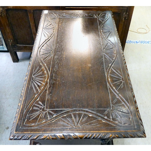 24 - A 1930s stained oak monk's bench with a hinged seat, over a carved and panelled front  30