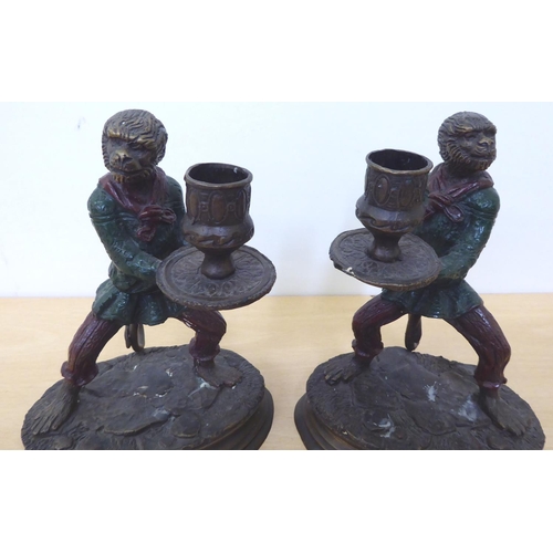 245 - A pair of modern cast bronze novelty candlesticks, fashioned as monkeys', in servant robes, on an ov... 