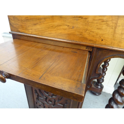 25 - A mid Victorian mahogany and walnut Davenport with a fret carved gallery, over a hide scriber set to... 