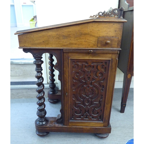 25 - A mid Victorian mahogany and walnut Davenport with a fret carved gallery, over a hide scriber set to... 