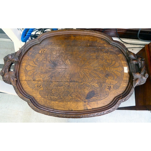 267 - A late 19thC carved Black Forest butler's tray with branch and leaf ornament, on a folding stand&nbs... 