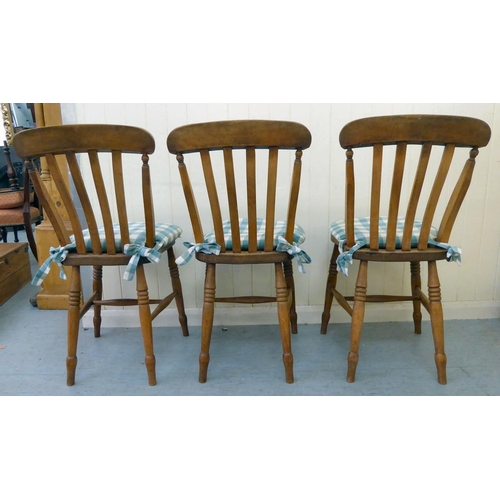 275 - A set of three modern Windsor beech and elm framed kitchen chairs with solid seats, raised on ring t... 