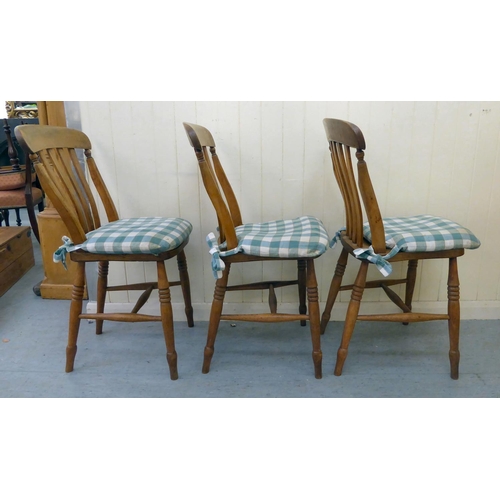 275 - A set of three modern Windsor beech and elm framed kitchen chairs with solid seats, raised on ring t... 