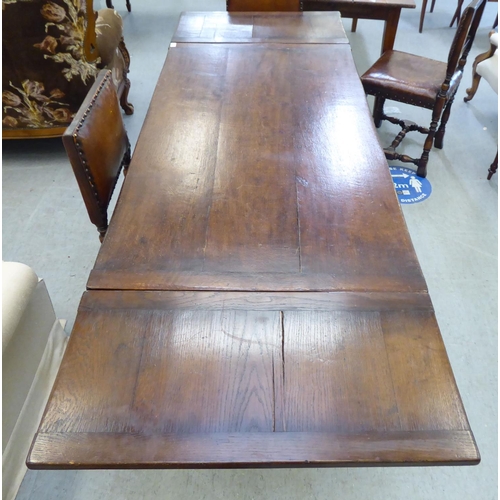 31 - An early/mid 20thC English style oak draw-leaf dining table, over a foliage carved frieze, turned an... 