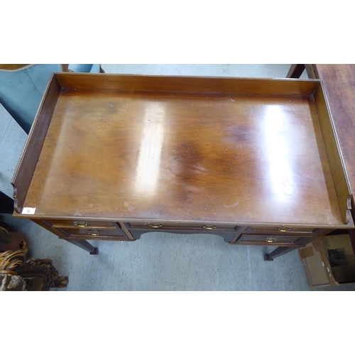 53 - A late Victorian mahogany five drawer kneehole dressing table with a low gallery upstand, raised on ... 