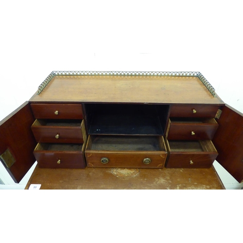 55 - An Edwardian mahogany bureau with a gallery, over an open shelf and drawer, flanked by two cupboard ... 