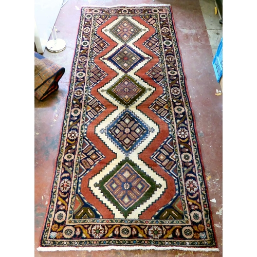 66 - A Persian design rug, decorated with five central guls, bordered by flora on a red ground  87