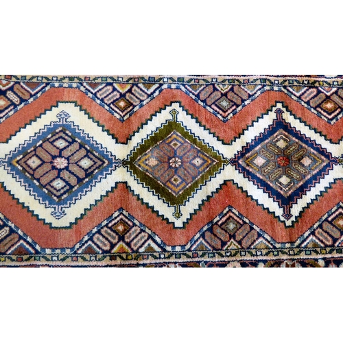 66 - A Persian design rug, decorated with five central guls, bordered by flora on a red ground  87