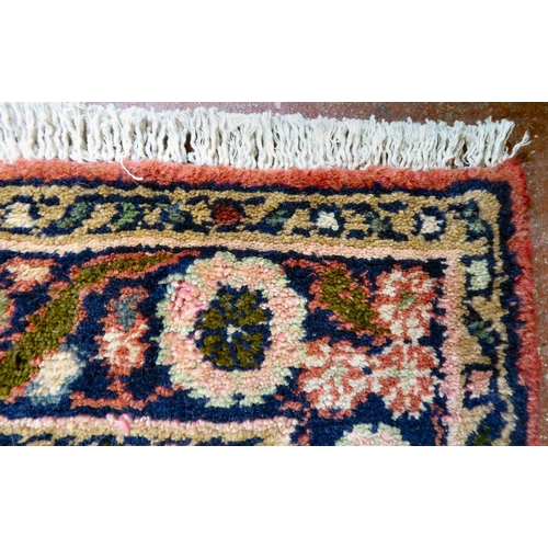 66 - A Persian design rug, decorated with five central guls, bordered by flora on a red ground  87