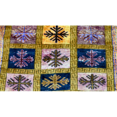 81 - An Iranian rug, decorated with twenty-one panels and snowflake design motifs, on a multi-coloured gr... 