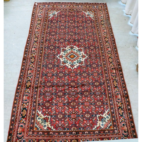 96 - A Persian design rug, decorated with a central medallion, surrounded by geometric designs, on a red ... 