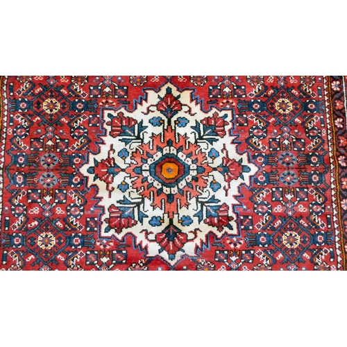 96 - A Persian design rug, decorated with a central medallion, surrounded by geometric designs, on a red ... 