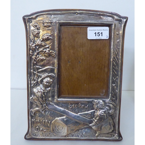 151 - A pair of silver plated photograph frames, the offset glazed apertures in nursery rhyme frames, embo... 