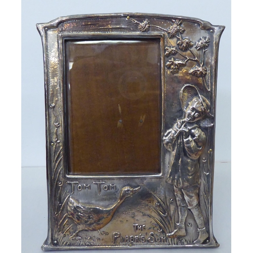 151 - A pair of silver plated photograph frames, the offset glazed apertures in nursery rhyme frames, embo... 