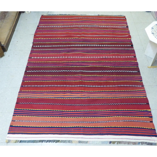 157 - A Kelim design rug, decorated with multi-coloured bands, on a red ground  80