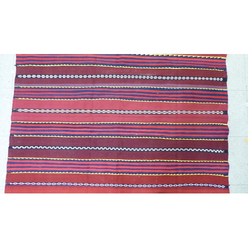 157 - A Kelim design rug, decorated with multi-coloured bands, on a red ground  80