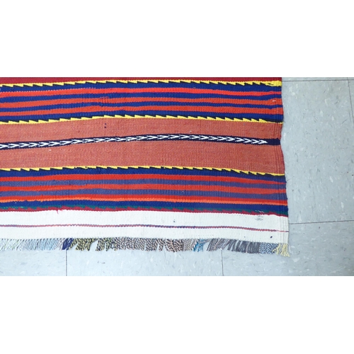 157 - A Kelim design rug, decorated with multi-coloured bands, on a red ground  80