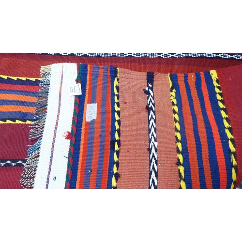 157 - A Kelim design rug, decorated with multi-coloured bands, on a red ground  80