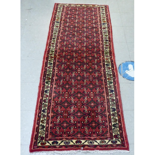 158 - A Persian Hamedan design runner, decorated with geometric and floral patterns, on a red ground  40