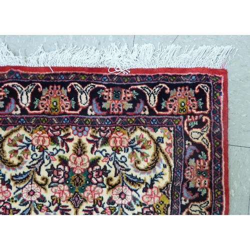 163 - A Persian Keshan design rug, decorated with floral patterns, on a cream and red ground  42