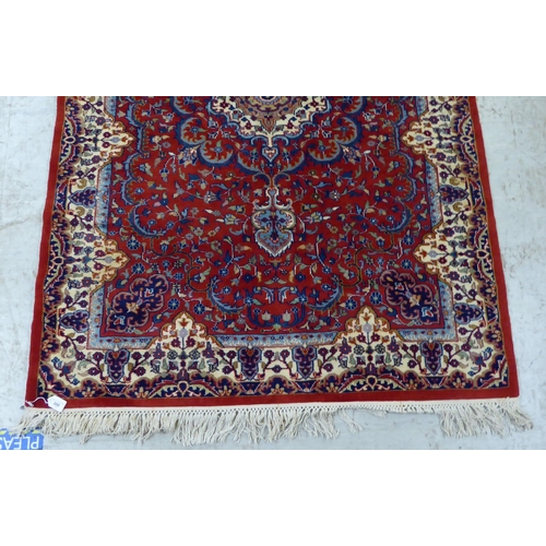 300 - A Persian rug, decorated with repeating floral designs, on a mainly red ground  50