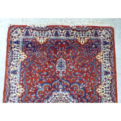 300 - A Persian rug, decorated with repeating floral designs, on a mainly red ground  50