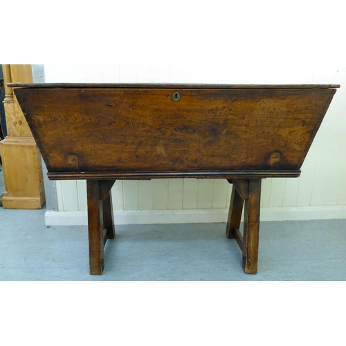 319 - A late 18th/early 19thC elm dough bin with angled sides and a removeable lid, raised on square legs ... 