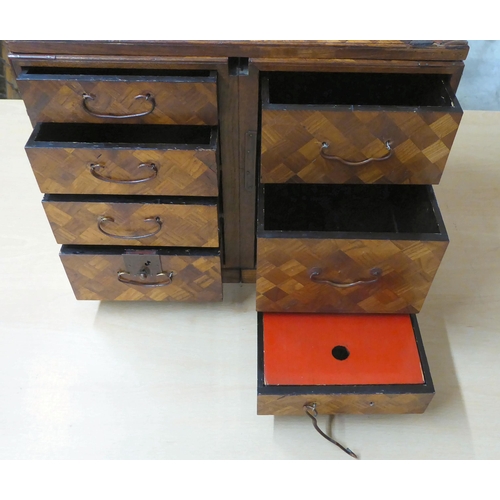 322 - A mid 20thC Japanese parquetry fruitwood veneered table top collector's chest with seven drawers, on... 