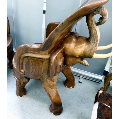 326 - A pair of modern novelty one-piece carved teak enclosed armchairs, fashioned as trumpeting elephants... 