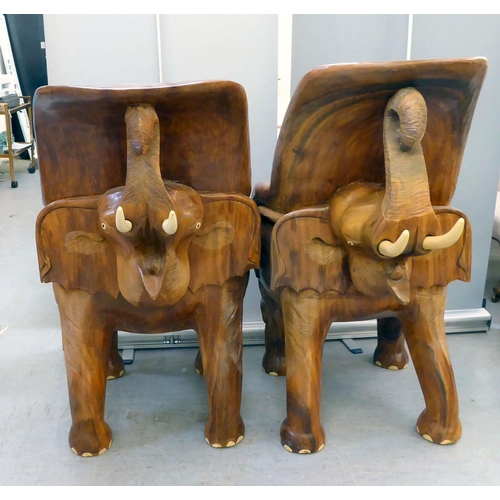 326 - A pair of modern novelty one-piece carved teak enclosed armchairs, fashioned as trumpeting elephants... 