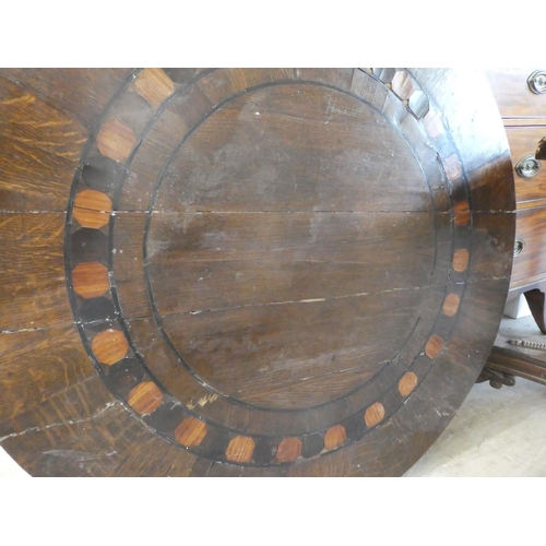 152 - A Victorian oak breakfast table with a decoratively inlaid centre, raised on a triform pillar, an in... 