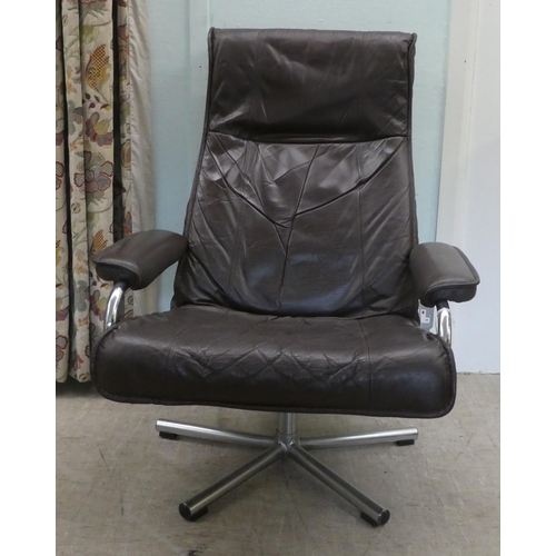 273 - A circa 1970s Norwegian Skoghaug Industries brown hide upholstered rotating arm chair, raised on a s... 