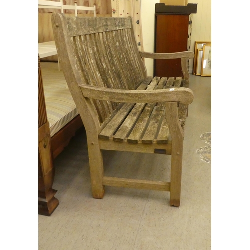 347 - A weathered, slatted teak garden bench, raised on square legs  60