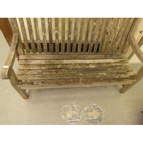 347 - A weathered, slatted teak garden bench, raised on square legs  60