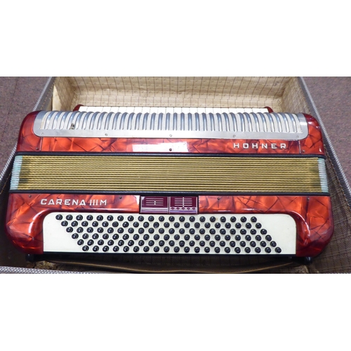 114 - A Hohner Carena IIIM, red marble effect cased piano accordion with a travel case