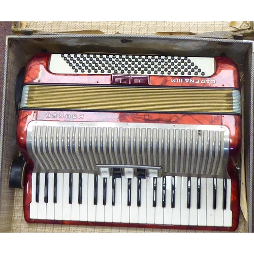 114 - A Hohner Carena IIIM, red marble effect cased piano accordion with a travel case