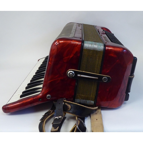 114 - A Hohner Carena IIIM, red marble effect cased piano accordion with a travel case