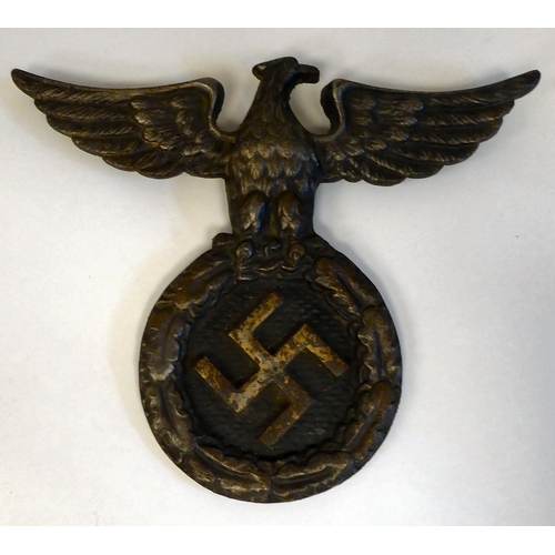 126 - A German Nazi era brass horn; a bronze cycling horn; and a spreadeagle and swastika iron vehicle emb... 