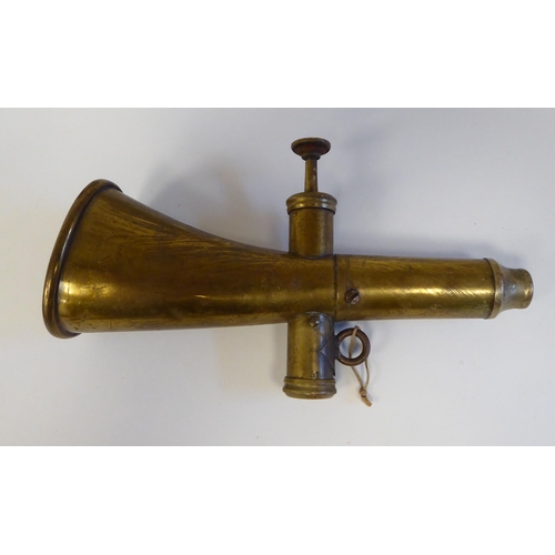 126 - A German Nazi era brass horn; a bronze cycling horn; and a spreadeagle and swastika iron vehicle emb... 