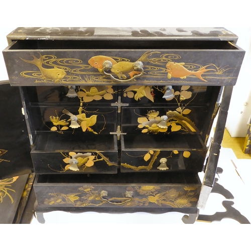 153 - An early 20thC Japanese black lacquered and gilded table cabinet, traditionally decorated in chinois... 