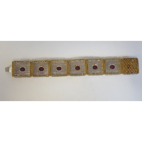 156 - A bi-coloured metal tablet link bracelet, set with a ruby coloured stone  boxed with carton