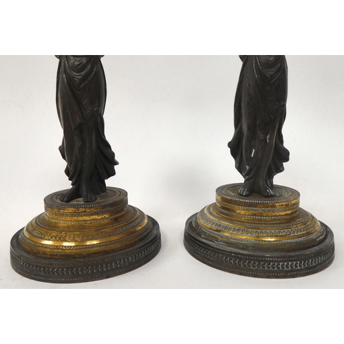 157 - A pair of mid Victorian taperstick holders, fashioned as cast and patinated female figures, each wea... 