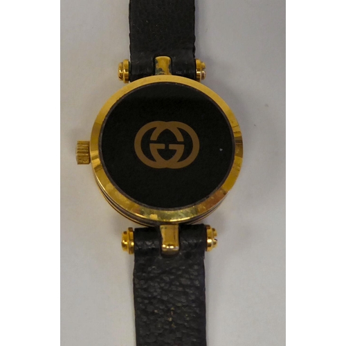 278 - A lady's Gucci gilded and black cased wristwatch, faced by a black Roman dial, on a dedicated black ... 