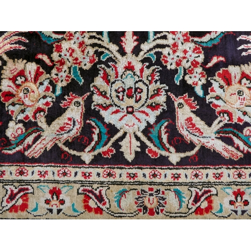 397 - A Persian pure silk rug, decorated with birds, flora and foliate, on a red ground with a black borde... 