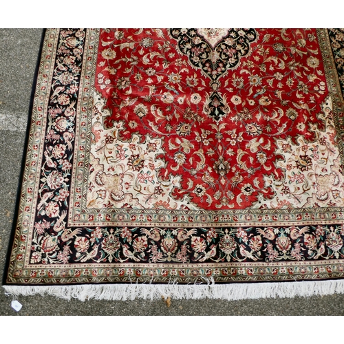 397 - A Persian pure silk rug, decorated with birds, flora and foliate, on a red ground with a black borde... 