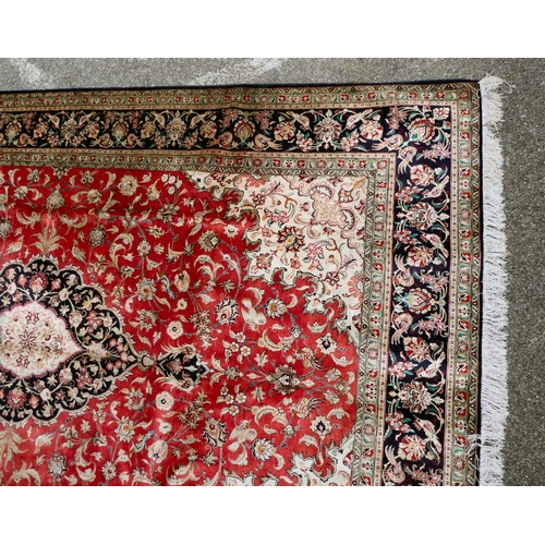 397 - A Persian pure silk rug, decorated with birds, flora and foliate, on a red ground with a black borde... 